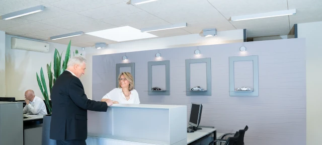 Heller Empfangsbereich im Autohaus mit Beratungsgespräch am modernen Tresen.
