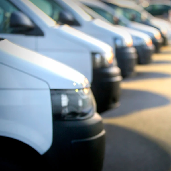 Reihe weißer Transporter auf einem Parkplatz, Fuhrpark für Gewerbe und Fahrzeugvermietung.