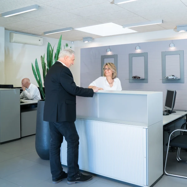 Heller Empfangsbereich im Autohaus mit Beratungsgespräch zwischen Kunde und Mitarbeiterin.